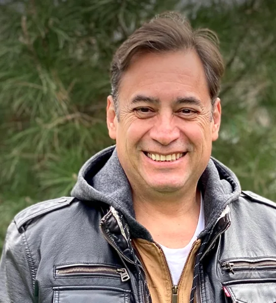 Dr. Gian Villatoro outdoors, smiling, in a leather jacket