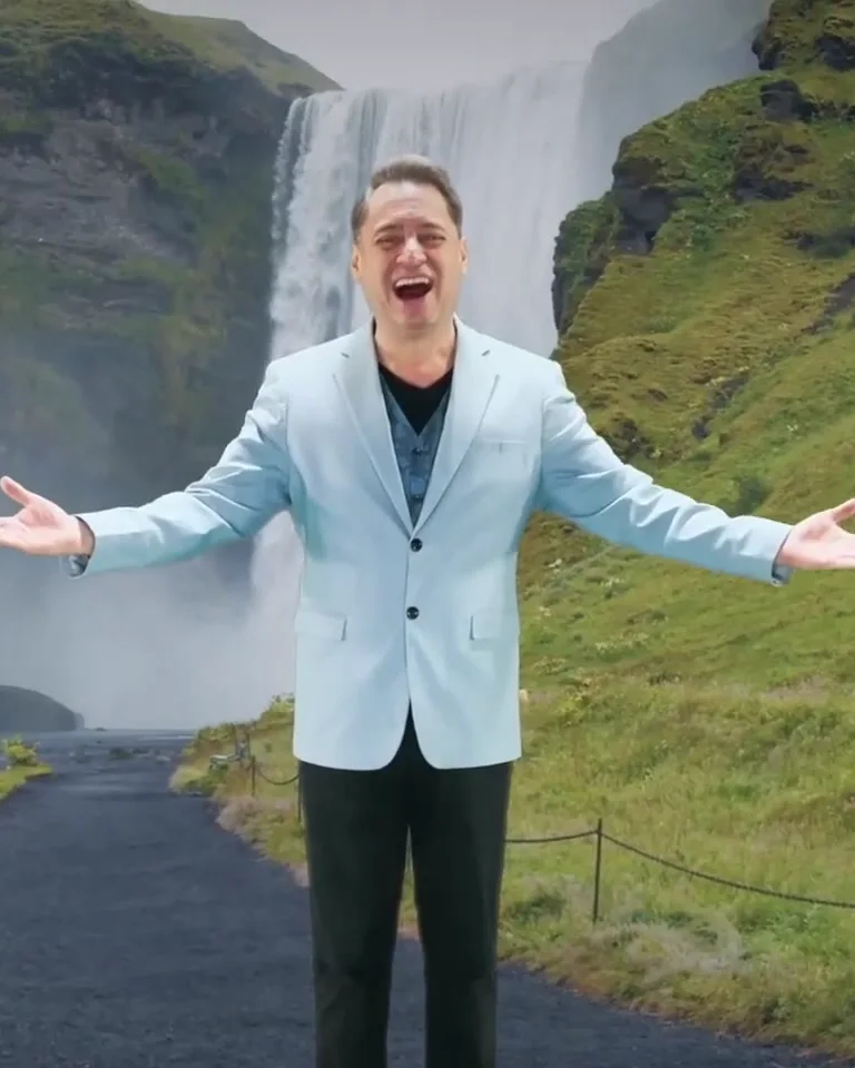 Dr. Gian worshiping with open arms in front of a waterfall
